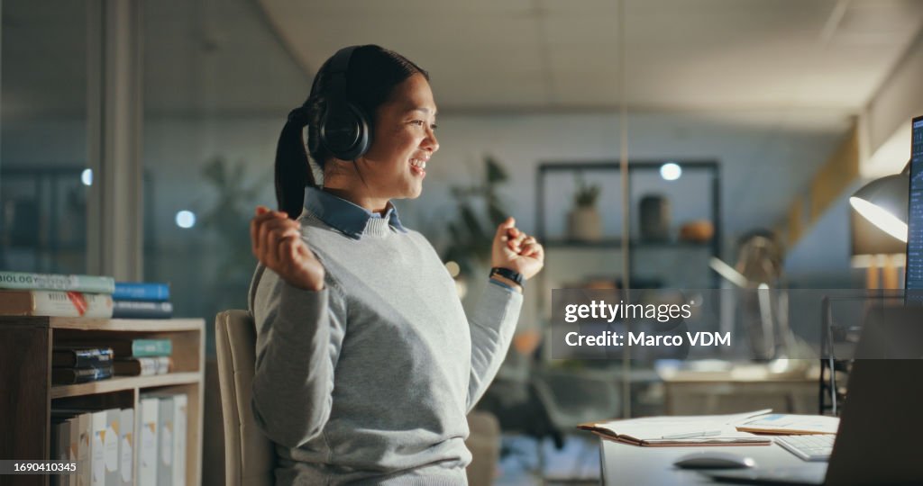 Dancing, night and business woman streaming on computer with headphones happy for music and working late in an office. Audio, dark and excited employee on internet with online freedom in a company