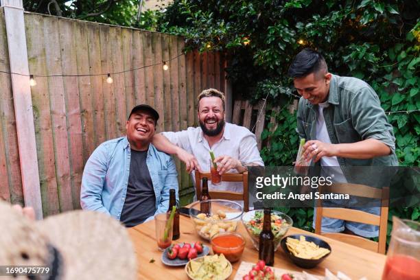 three friends laughing with drinks in their hands - garden brunch stock pictures, royalty-free photos & images