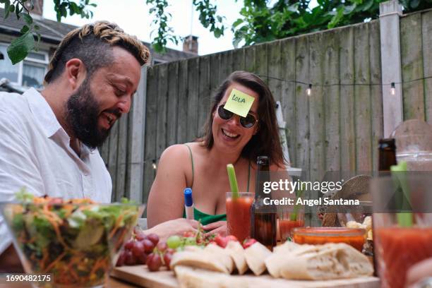 two friends enjoying an afternoon of games with a post-it on their foreheads - festival grounds stock pictures, royalty-free photos & images