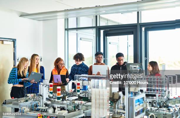 multiracial group of students listening to tutor explaining about conveyor belt - greater london stock pictures, royalty-free photos & images