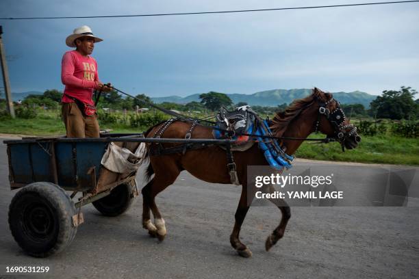 Man rides his horse-pulled cart along a road in Santiago de Cuba in eastern Cuba, on September 24, 2023.