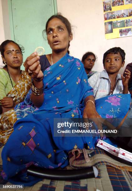 An Indian sex worker displays a condom watched by her son, during a sex worker meeting, a sex worker group which promotes condom use as part of an...