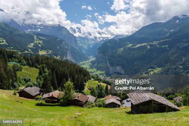 typical alpine wooden barn on green pasture with high cliffs in background, lauterbrunnen valley, bernese oberland, switzerland, europe - staubbach falls stock pictures, royalty-free photos & images
