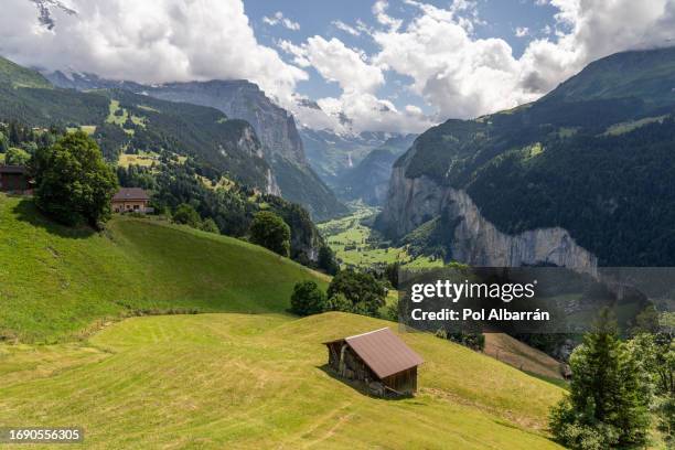 typical alpine wooden barn on green pasture with high cliffs in background, lauterbrunnen valley, bernese oberland, switzerland, europe - staubbach falls stock pictures, royalty-free photos & images