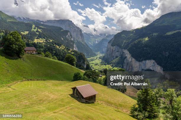 typical alpine wooden barn on green pasture with high cliffs in background, lauterbrunnen valley, bernese oberland, switzerland, europe - staubbach falls stock pictures, royalty-free photos & images