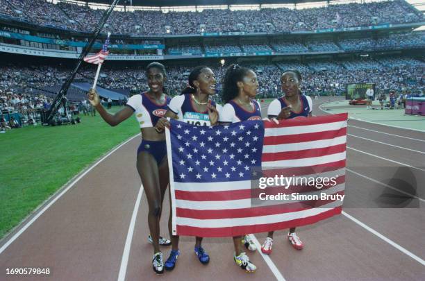 Gwen Torrance, Inger Miller, Gail Devers and Christy Gains of the United States celebrate with the Stars and Stripes flag after winning the gold...