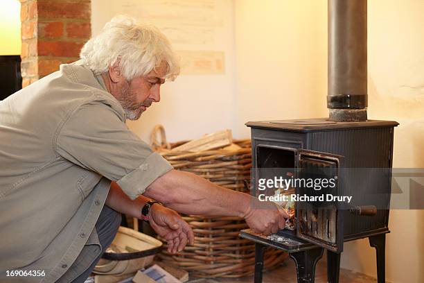 man lighting fire in woodburner - thetford stock pictures, royalty-free photos & images