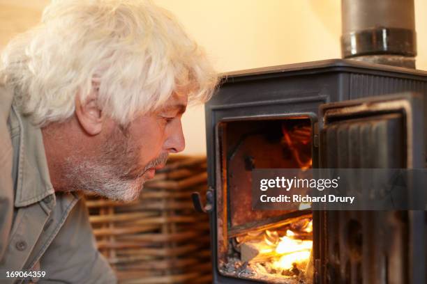 man blowing on fire in woodburner - thetford stock pictures, royalty-free photos & images