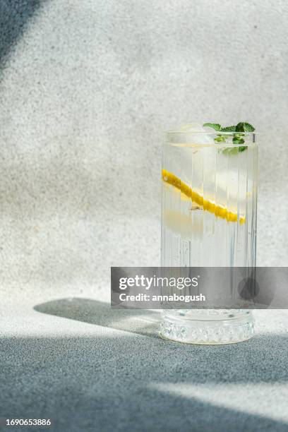 glass of sparkling lemon and mint water or alcohol and tonic cocktail - sprudelgetränk stock-fotos und bilder