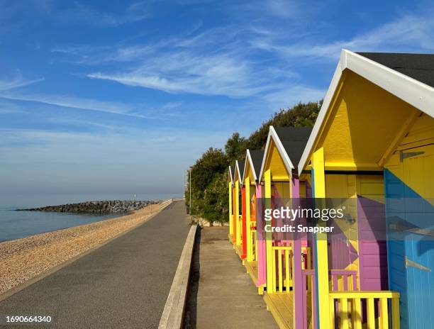 row of multi coloured wooden beach huts on beach, folkestone, kent, england, uk - フォークストーン ストックフォトと画像