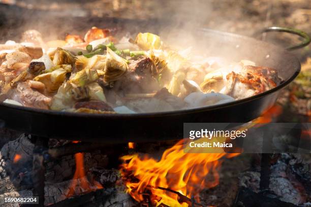 paella mit meeresfrüchten, die über einem holzfeuer gekocht wird - fischmousse stock-fotos und bilder