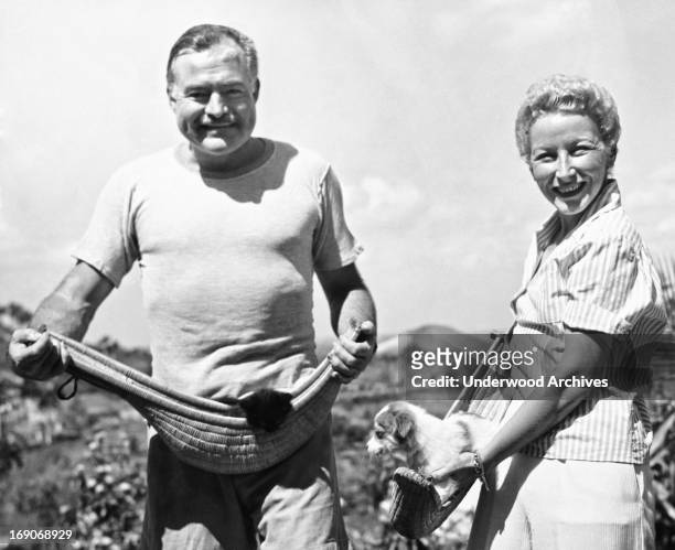 Author Ernest Hemingway and his fourth wife, Mary Welsh, hold their pets in jai alai baskets on the Hemingway farm in San Francisco de Paulo, Havana,...