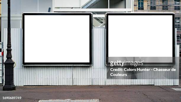two empty white advertising panels on a white corrugated iron wall with an asphalt street and a retro-style street light in paris, france - france et panneaux de signalisation photos et images de collection