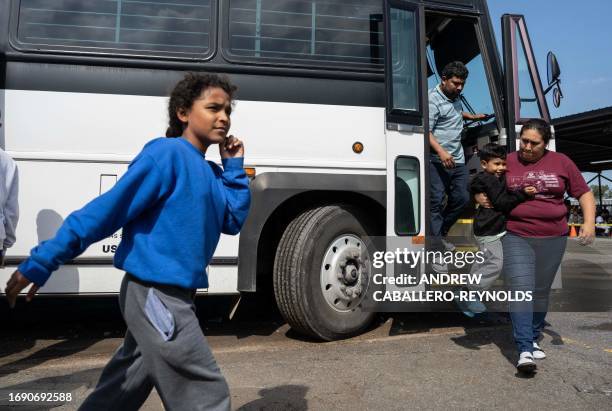 Migrants recently processed by the US Customs and Border Patrol get off a bus at a transposition assistance center in Eagle Pass, Texas on September...