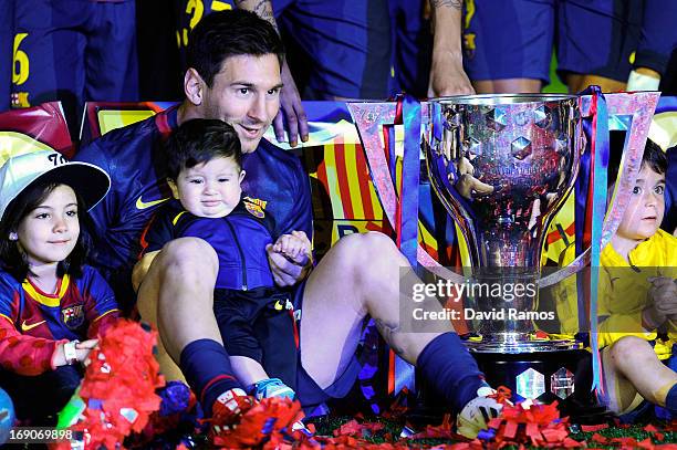 Lionel Messi of FC Barcelona holds his son Thiago as they sit next to the trophy during the celebration after winning the Spanish League after the La...