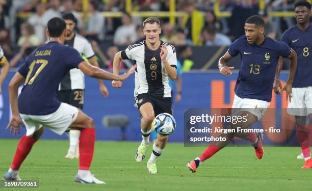 William Saliba of France and Florian Wirtz of Germany and Jean-Clair Todibo of France battle for the ball during the international friendly match...