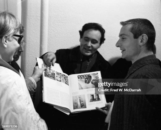 From left, American Pop artists Andy Warhol , Robert Indiana, and Roy Lichtenstein flip through an art book as they attend an exhibit at the Iolas...