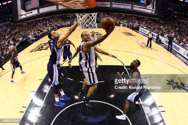 Tony Parker of the San Antonio Spurs drives for a shot attempt against Austin Daye and Tony Allen of the Memphis Grizzlies during Game One of the...