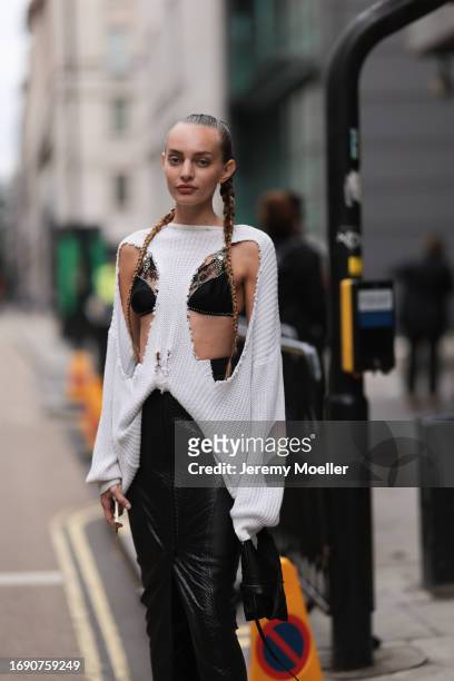 Fashion Week Guest was seen wearing a black leather skirt, a black bra with diamond bracelets, a black bag, two big pigtails and a white oversized...