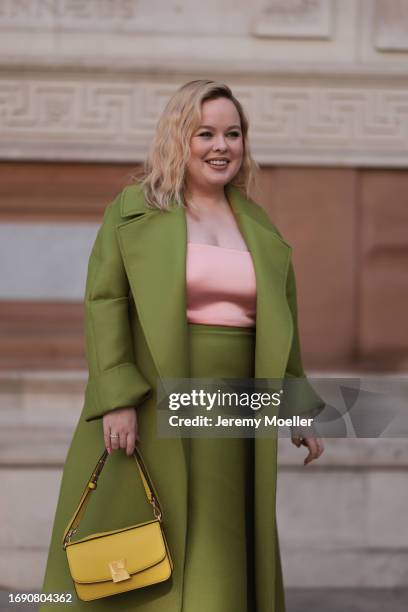 Nicola Coughla was seen wearing black shoes, a long green skirt, a rose strapless top, a yellow bag and a matching green coat before Emilia Wickstead...