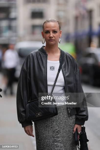 Fashion week guest was seen wearing a grey skirt, a white Loewe top, a black leather jacket as well as silver earrings and a black chanel boy bag...