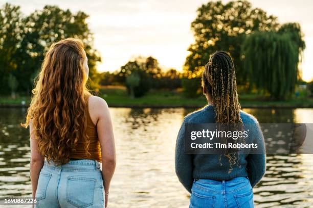 two women looking at sunset view - brood stock-fotos und bilder