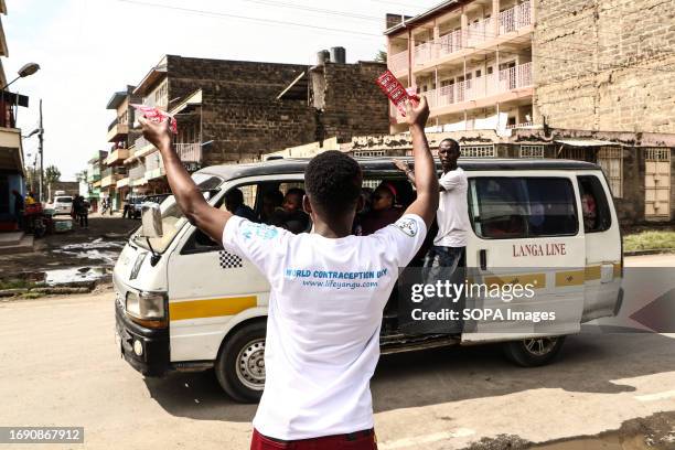 Volunteer waves while holding condoms and requesting people to pick them during the national celebrations of The World Contraception Day. According...