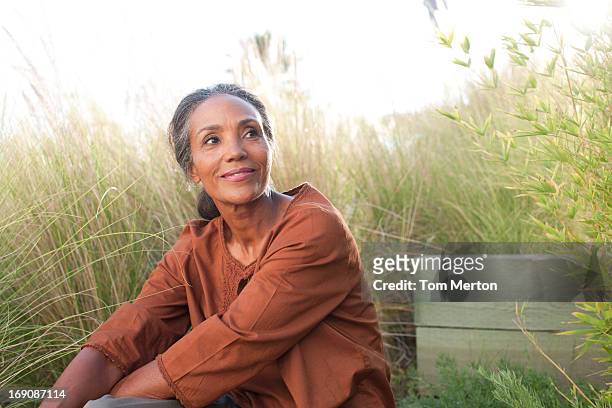 tranquila mujer sentada en el soleado campo - tranquilidad fotografías e imágenes de stock