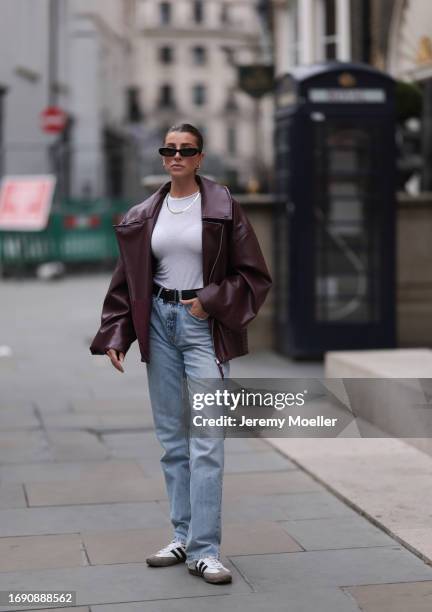 Fashion week guest was seen wearing black and white adidas samba sneaker, a denim jeans, a black belt, a white top with a yellow gold chain, dark...