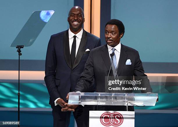 Retired NBA player and radio host John Salley looks on as sportscaster Jim Hill speaks at the podium during the 28th Anniversary Sports Spectacular...