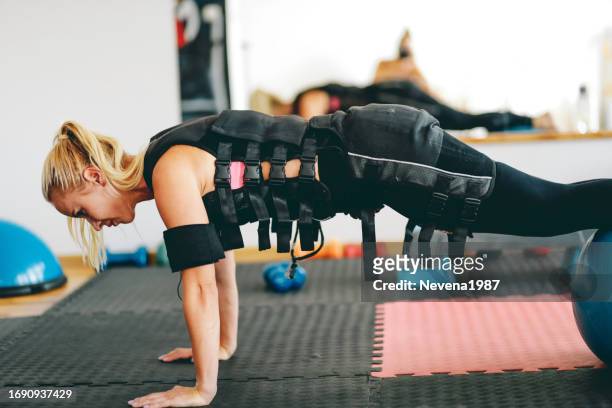 frau, die übungen im elektrischen muskelstimulationsanzug macht - ems sport stock-fotos und bilder