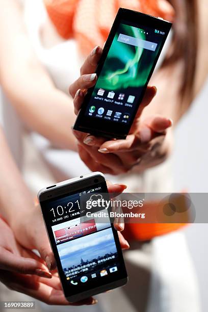 Models display KDDI Corp.'s au brand smartphones HTC J One HTL22, manufactured by HTC Corp., bottom, and Urbano L01, manufactured by Kyocera Corp.,...