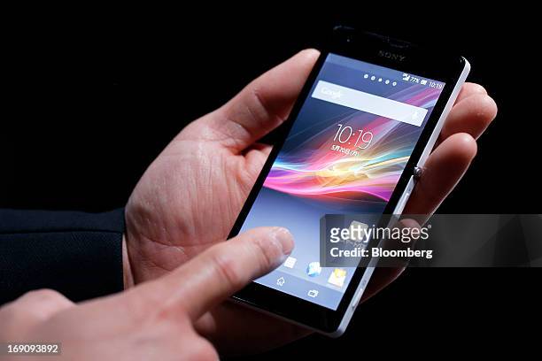 An employee demonstrates KDDI Corp.'s au brand Xperia UL SOL22 smartphone, manufactured by Sony Mobile Communications, during the unveiling of the...