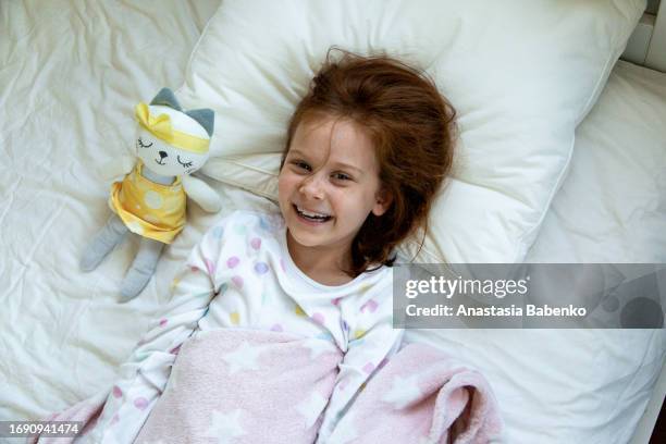 girl laying in a bed with stuffed toy - stuffed toy stock pictures, royalty-free photos & images