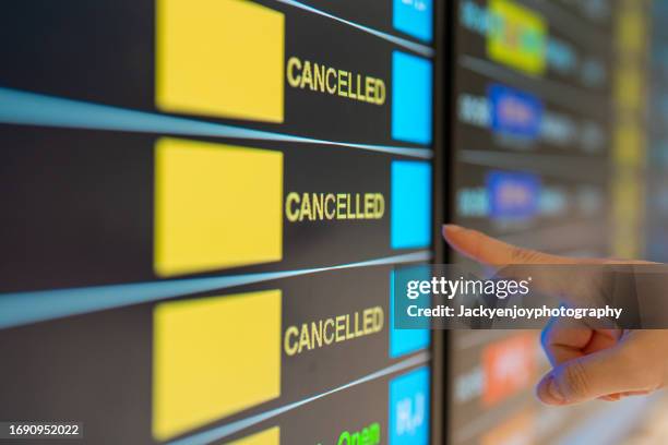 illuminated on the airport arrivals display is a flight cancellation. - cancelamento imagens e fotografias de stock