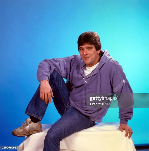 Portrait of English actor Steve Alder as he poses in front of a blue background, West Ham, England, February 6, 1986.