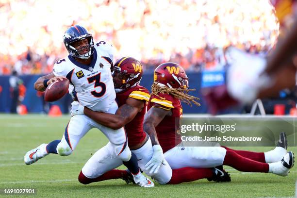 Montez Sweat and Chase Young of the Washington Commanders pressures Russell Wilson of the Denver Broncos at Empower Field At Mile High on September...