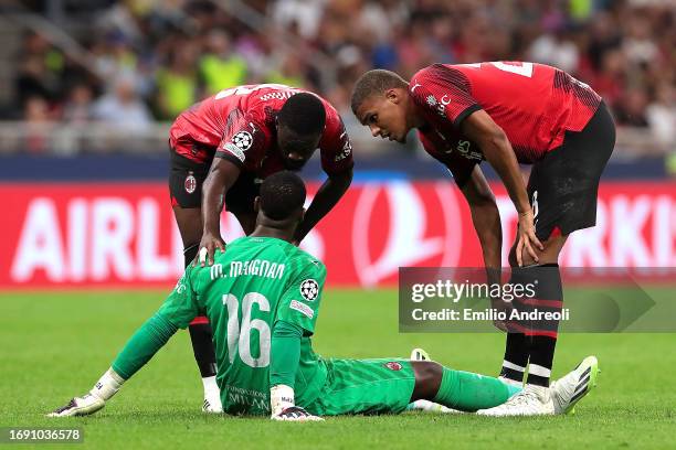 Mike Maignan of AC Milan speaks with Fikayo Tomori and Malick Thiaw of AC Milan after going down with an injury during the UEFA Champions League...