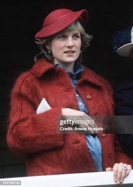 Diana, Princess of Wales, is 7 months pregnant and wearing a maroon coat and saucer hat, as she watches the Grand National at Aintree race course on...