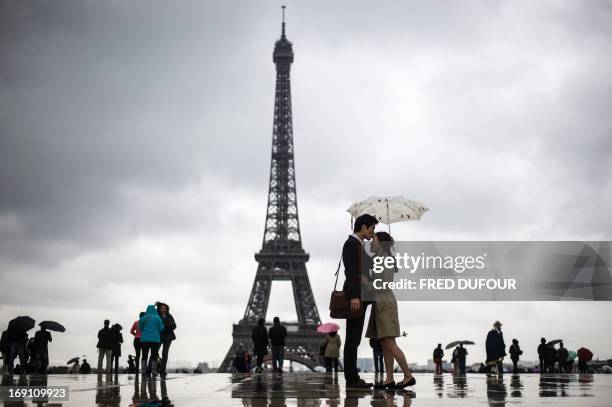 People gather on the Trocadero Square in front of the Eiffel Tower on a rainy day, on May 20 in Paris. AFP PHOTO / FRED DUFOUR