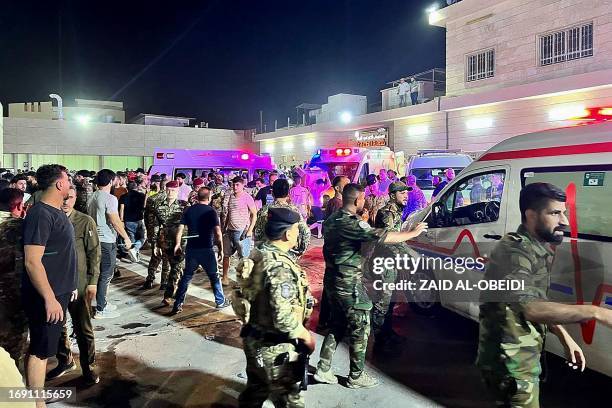 Soldiers and emergency responders gather around ambulances carrying wounded people after a fire broke out during a wedding at an event hall, outside...