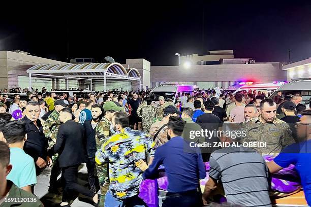 Soldiers and emergency responders among others gather around ambulances carrying wounded people after a fire broke out during a wedding at an event...