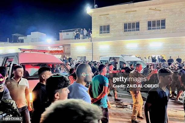 Soldiers and emergency responders among others gather around ambulances carrying wounded people after a fire broke during a wedding at an event hall,...