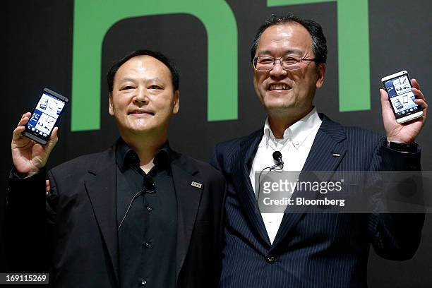Peter Chou, chief executive officer of HTC Corp., left, and Takashi Tanaka, president of KDDI Corp., hold the company's HTC J One HTL22 smartphones...