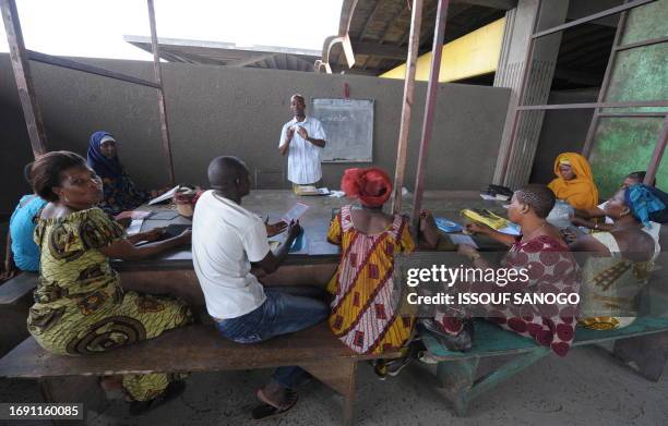 Market workers attend a class on October 28, 2008 in the market of a popular quarter of Abidjan where stall holders have put aside their tasks during...