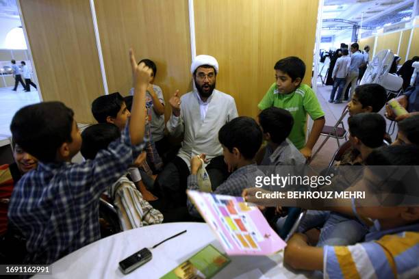 Iranian children listen to a clergyman as he answers their questions about religion at the International Koran exhibition at the Imam Khomeini grand...