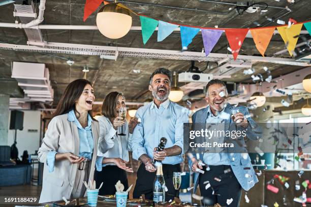 geschäftsleute, die mit party-popper im büro feiern - confetti explosion stock-fotos und bilder