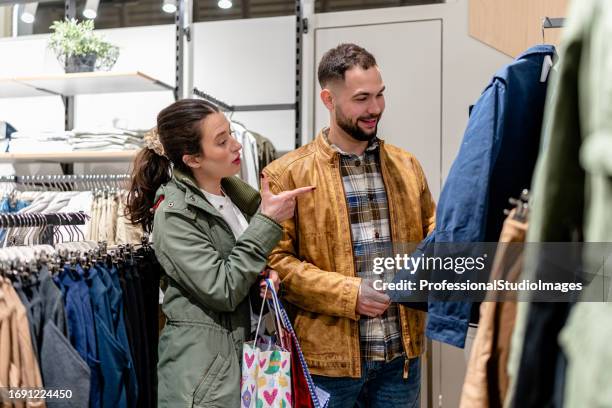 young couple enjoys shopping trip for new clothes at upscale store - boyfriend jacket stock pictures, royalty-free photos & images