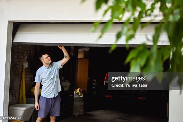 young adult man lifting gates of the garage. - automatic stock pictures, royalty-free photos & images