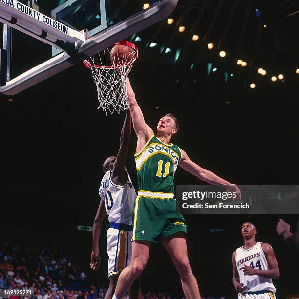 Detlef Schrempf of the Seattle Supersonics dunks against the Golden State Warriors circa 1995 at the Oakland-Alameda County Coliseum Arena in...